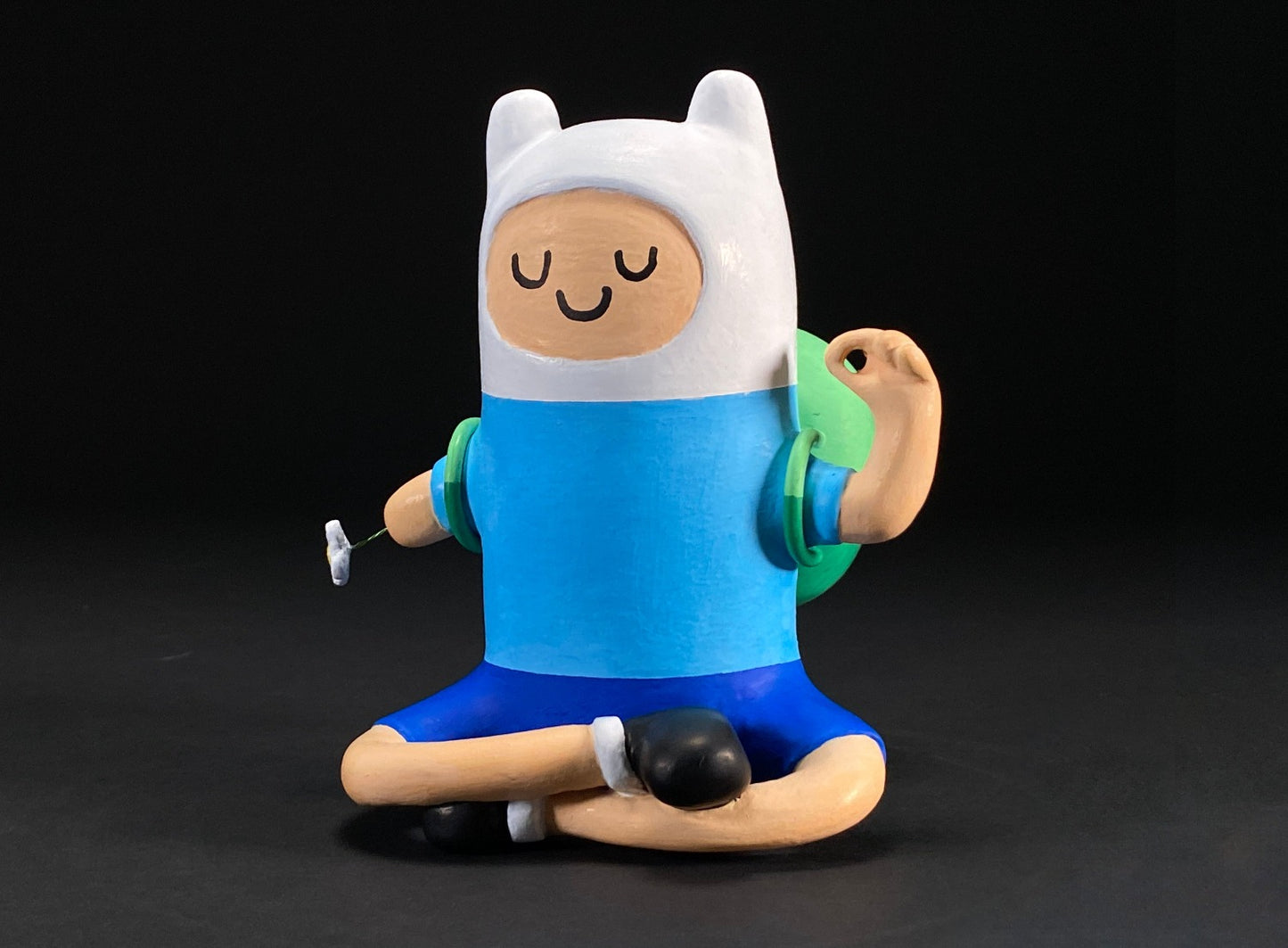 Side view of Finn statue sitting in meditative position. Finn is amputee on right arm with a flower growing.