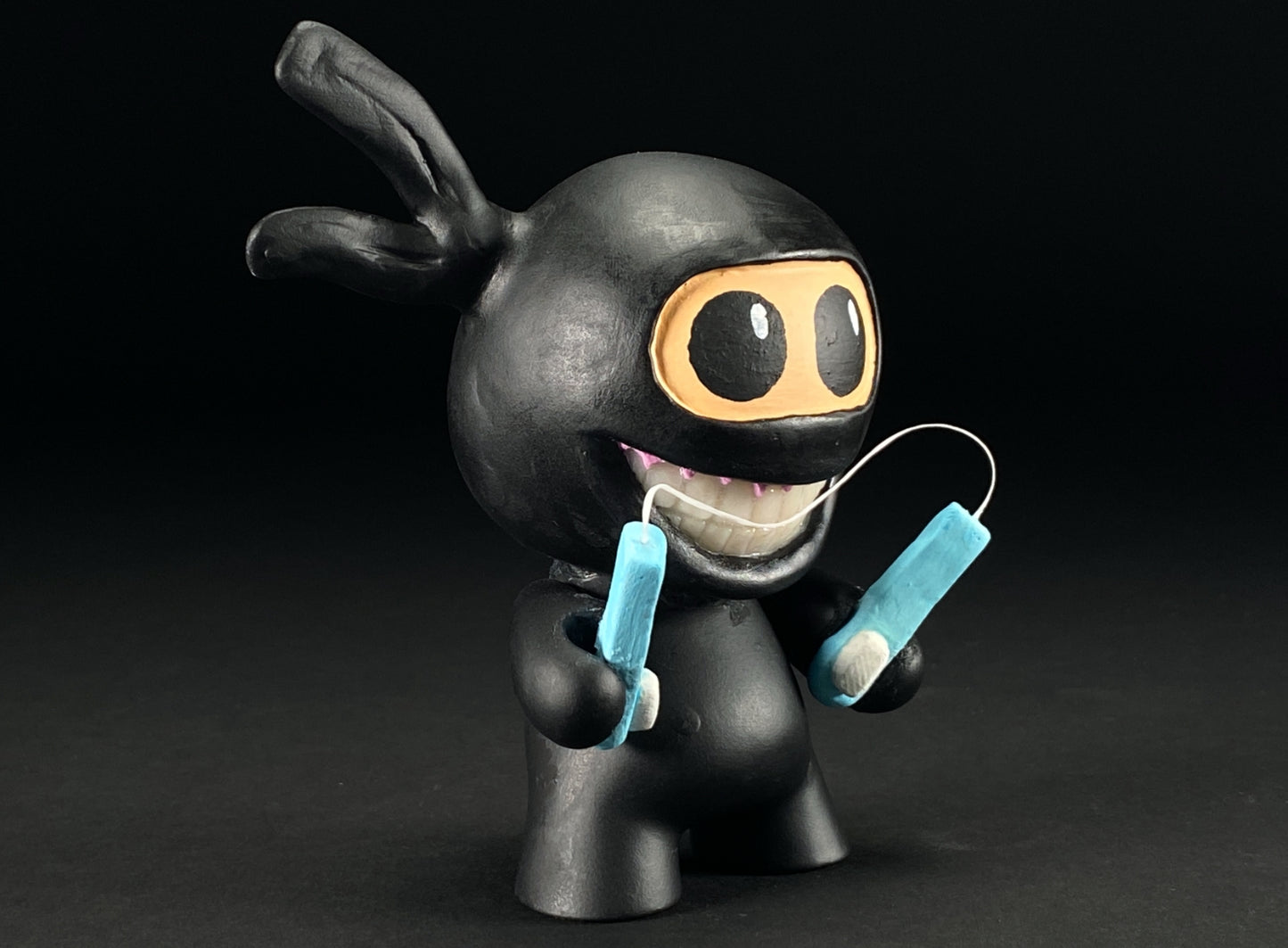 Right side of Tooth Ninja holding toothbrush nunchucks with floss connecting them.