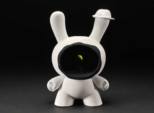 Photo of Dunny with giant black hole with a pea floating in the darkness. Wearing tin foil hat on one ear.